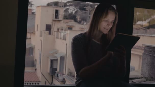 Mujer usando tableta PC sentado en el alféizar de la ventana — Vídeo de stock