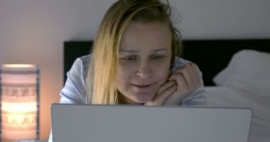 Kadın boş vakitlerini dizüstü bilgisayar ve filmle geçiriyor.