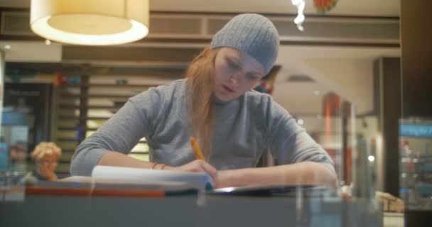 Frau im Café arbeitet mit Block und macht sich Notizen — Stockvideo