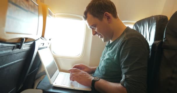 Jovem conversando no laptop no avião — Vídeo de Stock