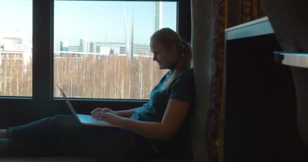 Woman uisng laptop by the window in hotel room — ストック動画