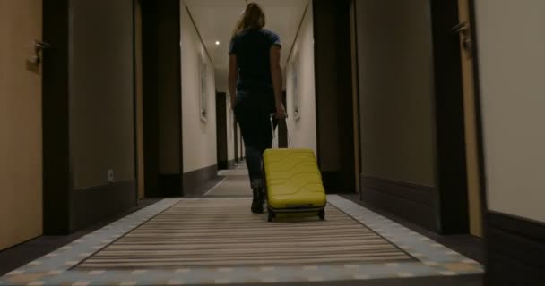 Woman with suitcase walking in hotel corridor — 图库视频影像