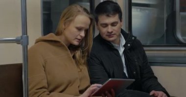 Young people using tablet computer in moving subway train