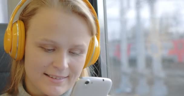 Женщина, использующая мобильный телефон и слушающая музыку в поезде — стоковое видео