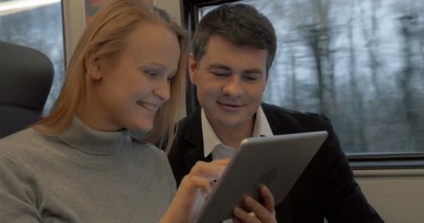 Jóvenes trabajando con almohadilla y hablando en el tren — Vídeo de stock