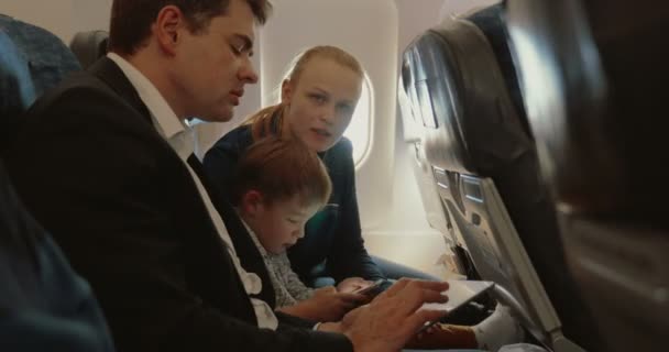 Занятые отец, ребенок и мать, путешествующие на самолете — стоковое видео