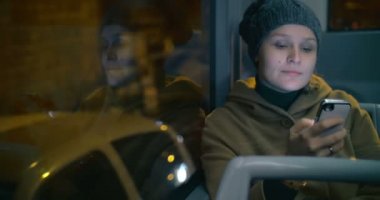 Young woman typing sms during bus ride