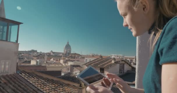 Mujer usando almohadilla en el balcón con vista a la ciudad — Vídeos de Stock