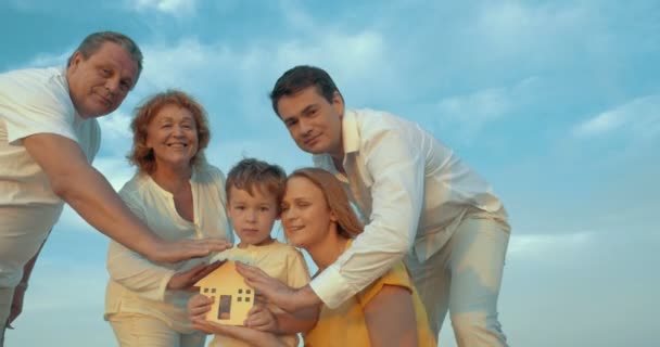 Familia cuidando de la pequeña casa de madera — Vídeo de stock