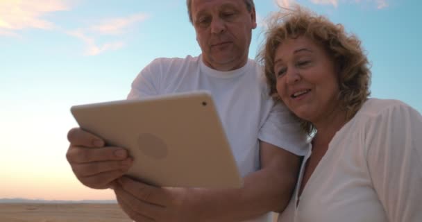 Uomo e donna anziani con tablet sulla spiaggia — Video Stock