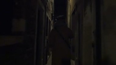 Woman running in narrow street at night
