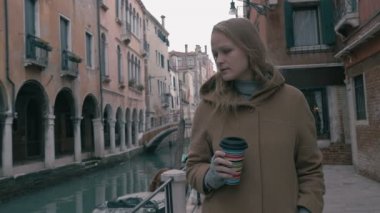 Woman with coffee walking in Venice