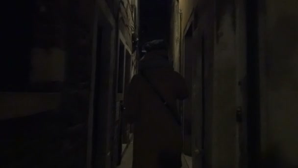 Woman running in narrow street at night — Stockvideo