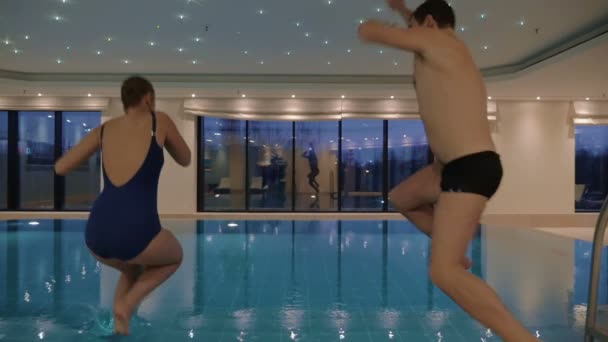 실내 수영장에 뛰어 들어가는 남자와 여자 — 비디오