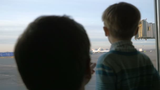 Far och son tittar ut genom fönstret på flygplatsen — Stockvideo