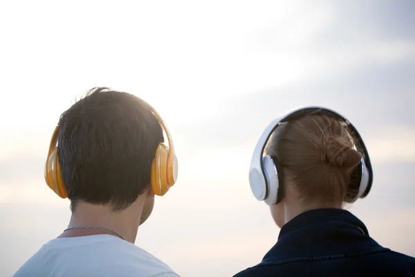 Молодые люди в наушниках наслаждаются музыкой на улице — стоковое фото