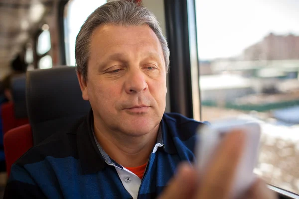 Человек, использующий мобильный телефон во время поездки на поезде — стоковое фото
