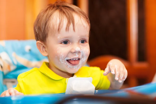 Criança feliz suja com iogurte creme — Fotografia de Stock