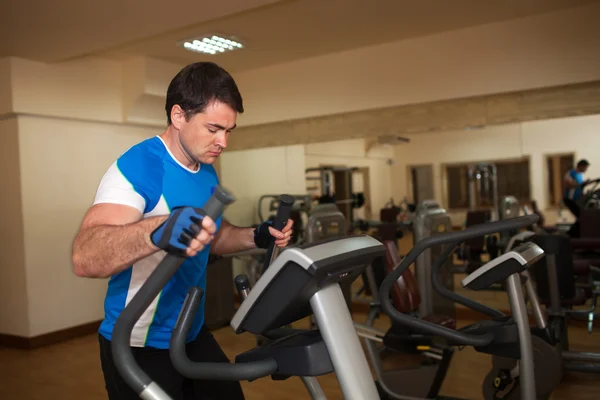 Man exercising on elliptical machine in gym — Stock Photo, Image