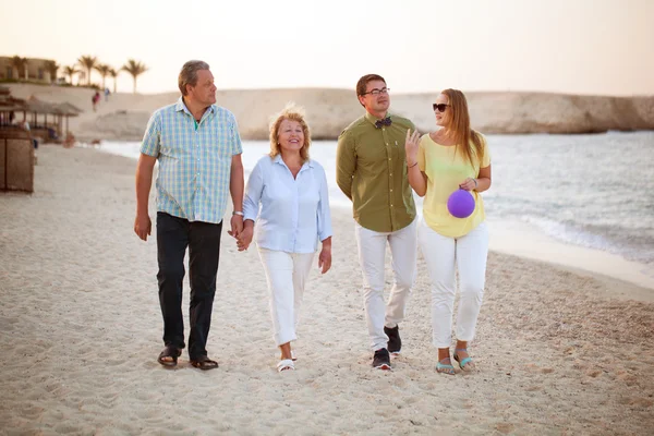 Junge und ältere Paare spazieren an der Küste entlang — Stockfoto