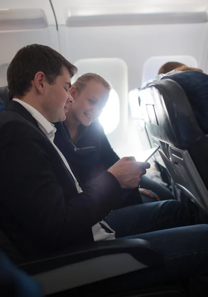 Young man and woman using cell phone in plane — Φωτογραφία Αρχείου