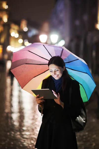 Mulher morena usando tablet na rua no dia chuvoso — Fotografia de Stock