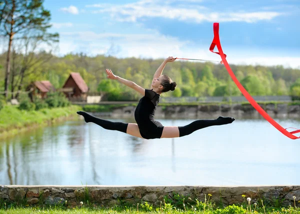 Chica gimnasta rítmica haciendo ejercicio con cinta al aire libre — Foto de Stock