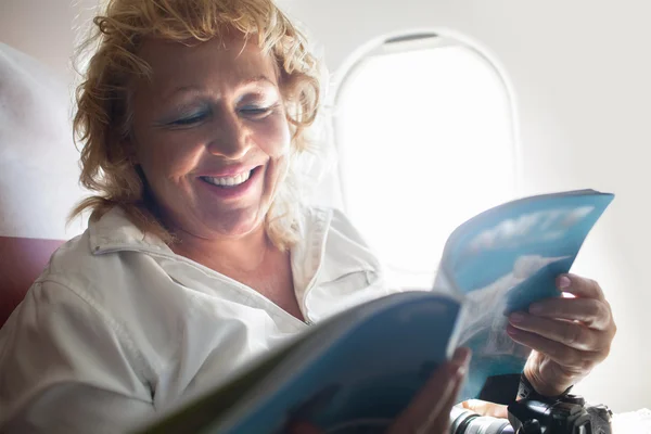 Femme mûre lecture Magazine sur un avion — Photo