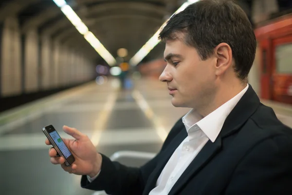 Young man reading sms on smartphone in underground — Stok fotoğraf