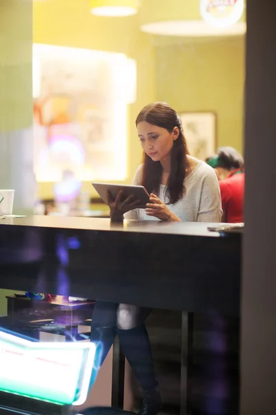 Молодая брюнетка с планшетом в кафе — стоковое фото