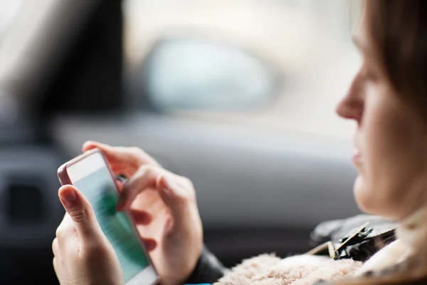 Woman uses smartphone in the car — Stock fotografie