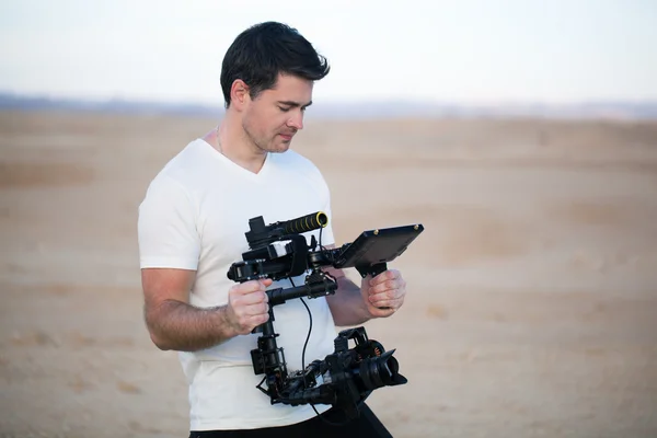 Young man using steadycam for shooting on beach — Stock fotografie