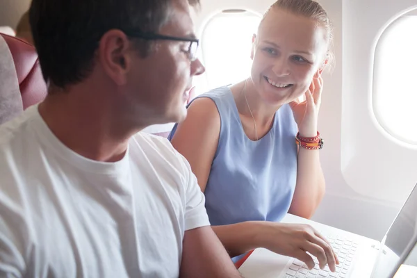 Happy young and woman with laptop in plane — Stock Photo, Image