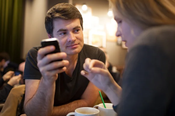 Hombre usando el teléfono móvil durante la reunión con la chica en la cafetería — Foto de Stock