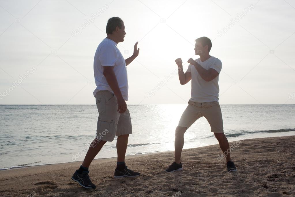Two men having boxing training on the beach