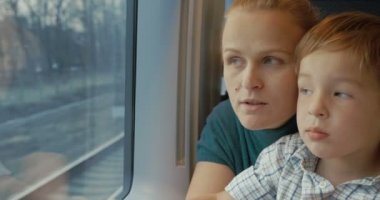 Anne ve oğlu tren penceresinden dışarı bakıyor