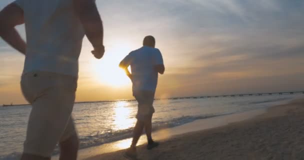 夕暮れ時のビーチ沿いのジョギング — ストック動画