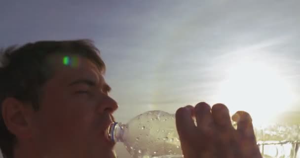 Молодой человек пьет воду на открытом воздухе на закате — стоковое видео