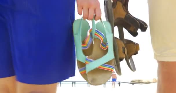 Paar spaziert mit Sandalen in der Hand am Strand — Stockvideo