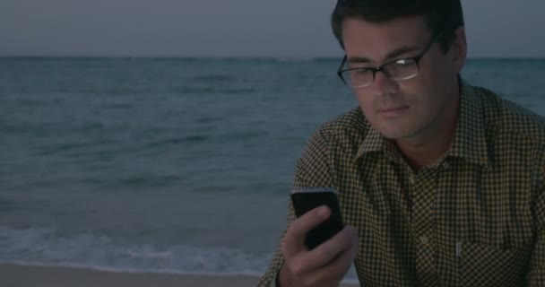 Hombre usando el teléfono inteligente junto al mar — Vídeos de Stock