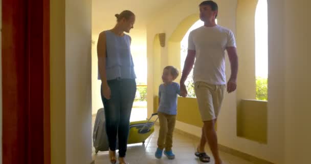 Familie rollt Rollkoffer entlang der Hotelpassage — Stockvideo