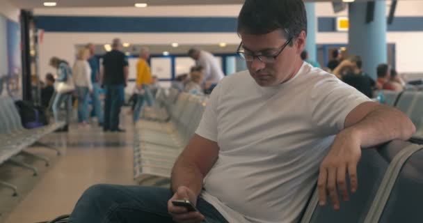 Молодий чоловік використовує мобільний телефон у лаунжі аеропорту — стокове відео