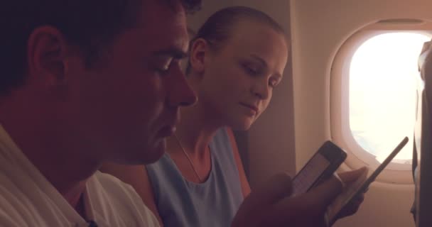 Young people using tablet PC and cell phone in plane — Stockvideo