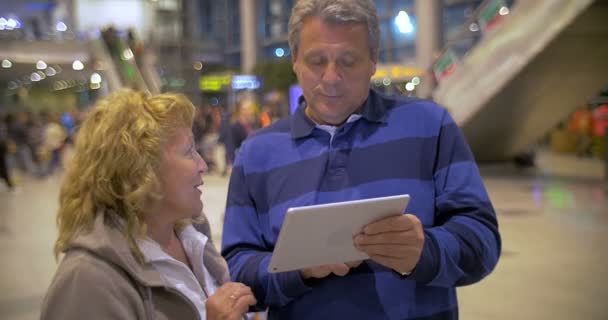 Старшая пара с яркими разговорами, используя блокнот в аэропорту — стоковое видео