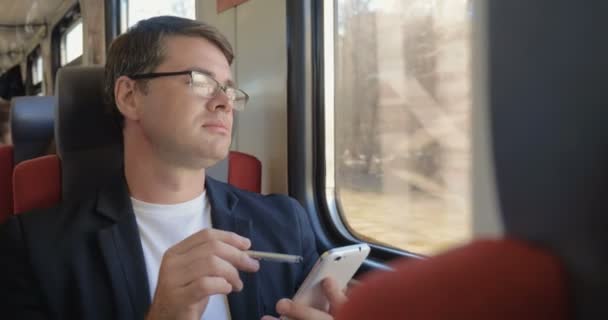 Człowiek z telefonem komórkowym korzystających z widoku z okna pociągu — Wideo stockowe
