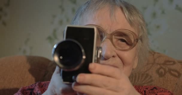 Elderly woman with retro camera at home — Stock Video