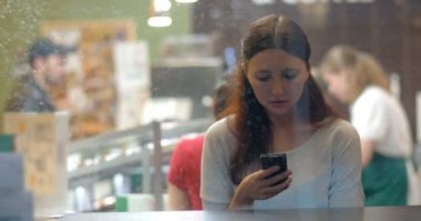 Woman exchanging messages on cell in cafe