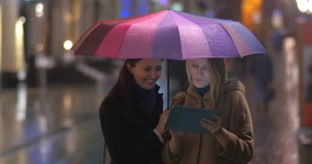 Freundinnen mit Tablet unterm Regenschirm