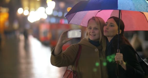 Женщины-подруги делают селфи под радужным зонтиком — стоковое видео