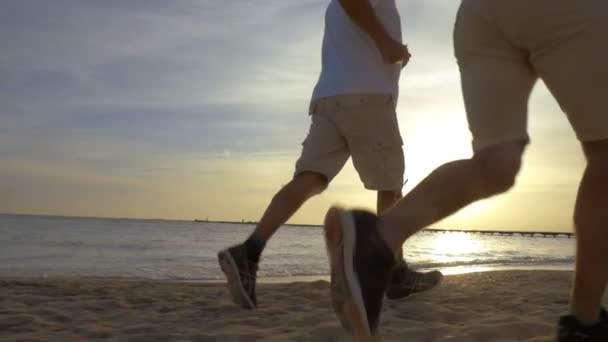 Двое мужчин бегают на пляже — стоковое видео